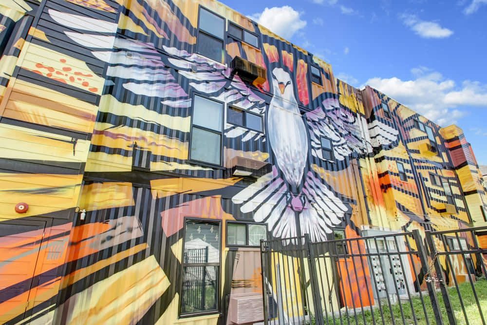 Colorful mural of a bird painted across the shipping containers at Ashley Lofts